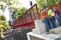 Workers install a 60-foot pedestrian bridge Friday on the Converse Junction Trail on the east side of Converse. Photo/Jeff Morehead