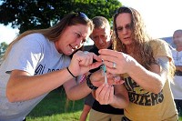 Kimberly Buck, left, a community outreach volunteer in Jackson County, shows Brenda and Brad Ahlbrand of Brownstown how to get a dose of naxolone into a syringe during a training and distribution event Monday at Harmony Park in Seymour. Staff photo by Zach Spicer