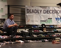 Tyler Lybert talks Tuesday about beating a heroin addiction. He spoke at Lake Center High School while surrounded by pairs of shows that represented lives lost to the drug. Staff photo by Damian Rico