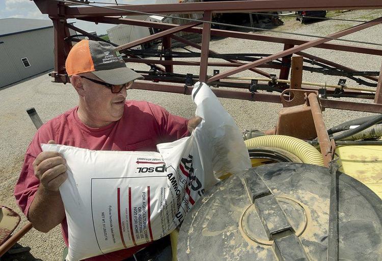 Weed control: Farmer Jeff Gormong pours an additive into a herbicide tank for his brother, Jason Gormong, so Jason can spray another one of the family’s fields on July 26 at their farm in southern Vigo County. Staff photo by Joseph C. Garza