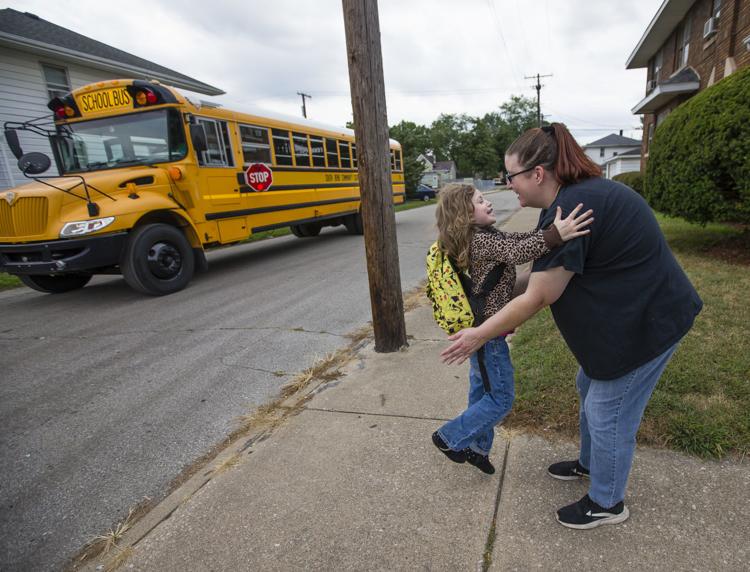 Second grader Vivianna Rozinski jumps into her mom Jennifer Rozinski’s arms after getting off the bus Wednesday on the west side of South Bend. Parents say transportation problems continue to plague the South Bend district. Tribune Photo/MICHAEL CATERINA