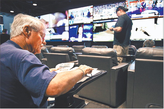 Robin Lawson, of Cicero, goes over his pro football sheet as he was one of the first patrons to place a bet at the sports betting area that opened Thursday at Harrah’s Hoosier Park Racing & Casino. Staff photo by John P. Cleary