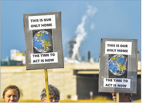 Activists raise their signs as they call for change during Friday’s Global Climate Strike in Jeffersonville. Supporters of the strike gathered together with handmade signs to spread their message to passing commuters. Staff photo by Tyler Stewart