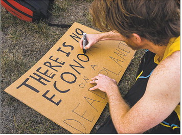 Phil Murray adds finishing touches to his sign before joining Friday’s Global Climate Strike at the corner of 10th and Spring streets in Jeffersonville. Staff photo by Tyler Stewart