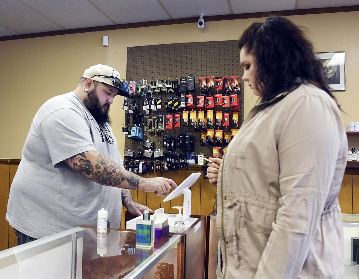 Aaron Goodson, the owner of Vintage Vapors, rings up a purchase for customer Danielle Clevenger in his north Anderson vape shop.  Stafff photo by John P. Cleary