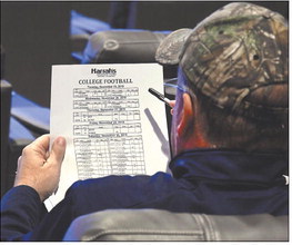 A patron studies a college football odds sheet at The Book. Staff photo by John P. Cleary