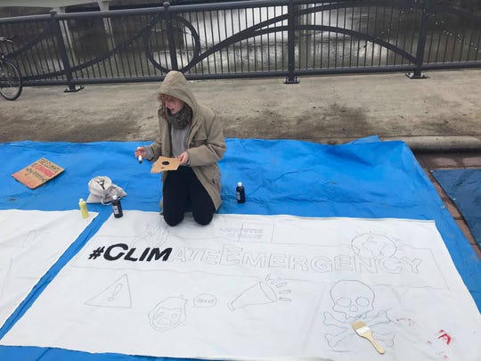 Polly Barks, a co-facilitator with the group Lafayette Climate, works on painting a banner that reads "#ClimateEmergency" during the Bridge Across the Climate Crisis strike. (Photo: Emily DeLetter/Journal & Courier)