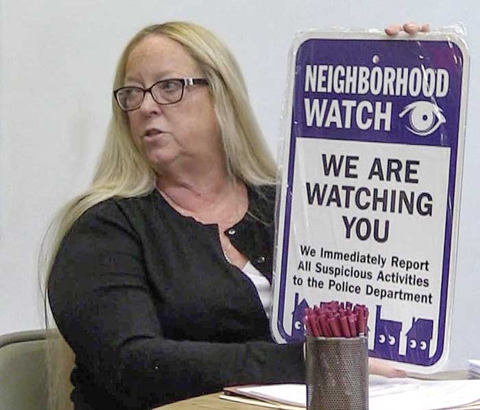 Dupont resident Robyn Meek (above) holds up a sign like the ones the community will post alerting potential criminals that the town has a Neighborhood Watch Group and all suspicious activity will be reported to police. (Photos by WKMNews)