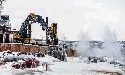 Lake Michigan waves crash near homes as construction crews work to build revetment walls in Long Beach on Thursday. Staff photo by Robert Franklin