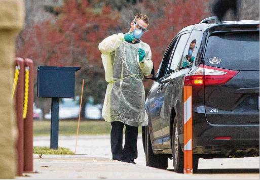 A health care worker Wednesday tests a patient for the coronavirus at a drive-through site outside the South Bend Clinic’s Immediate Care Center in Mishawaka. Staff photo by Robert Franklin