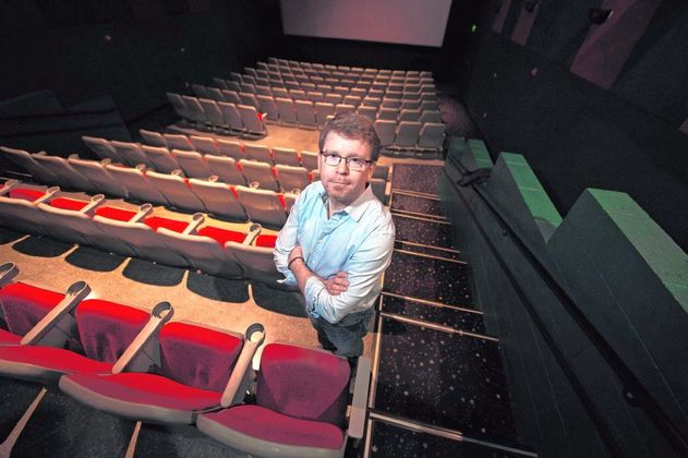 Legacy Cinema owner Cary Benbow stands among empty seats in a darkened theater at the complex in Greenfield. 'We're dead in the water,' he said. Staff photo by Tom Russo