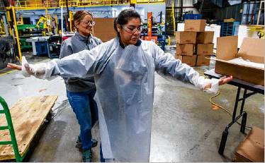Nisco worker Herminia Rayn tries on a hospital gown at the plant in Bremen. Staff photo by Robert Franklin
