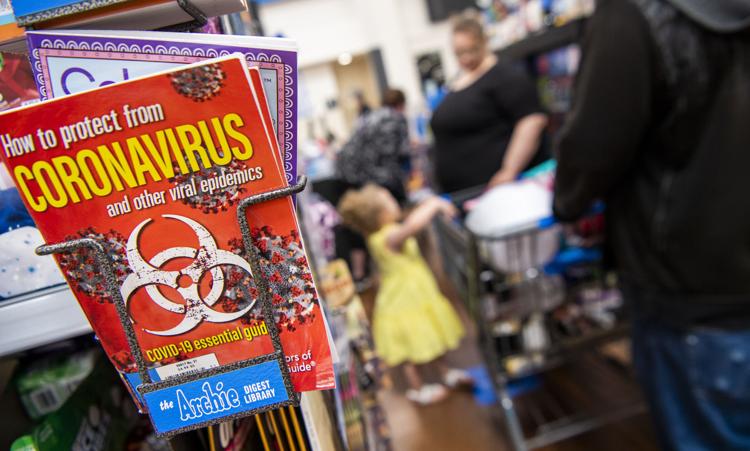 A coronavirus-based magazine sits at the checkout counter Friday as Sammantha Stickels, middle, Kevin Wood, off to right, and their daughter Leslie wait in line at Walmart. (Rich Janzaruk / Herald-Times)