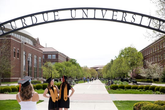 Kassie Zamora, left, takes a photo of Lauren Novak, center, and Staphanie Godoshian, right, as they pose for graduation photos by the Centennial Arch at Purdue University, Monday, May 4, 2020 in West Lafayette.  (Photo: Nikos Frazier | Journal & Courier)