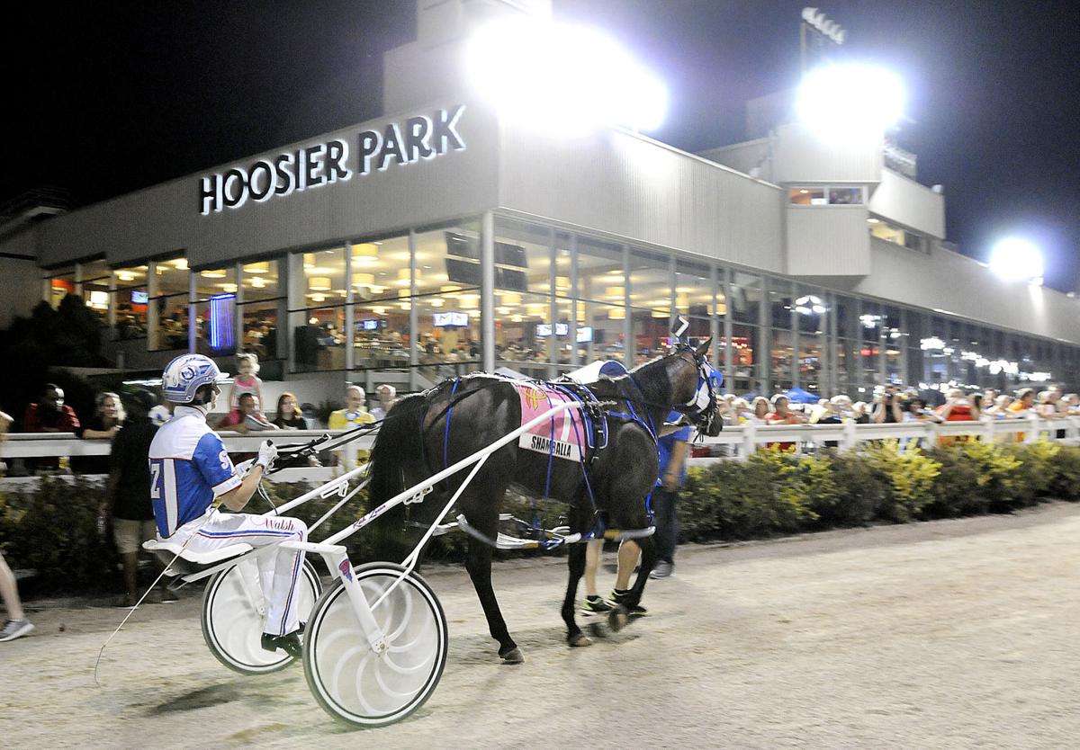 Horse and driver head out of the paddock area for the track in front of a large crowd for the running of the Dan Patch Invitational horse race at Hoosier Park in Anderson. Staff file photo