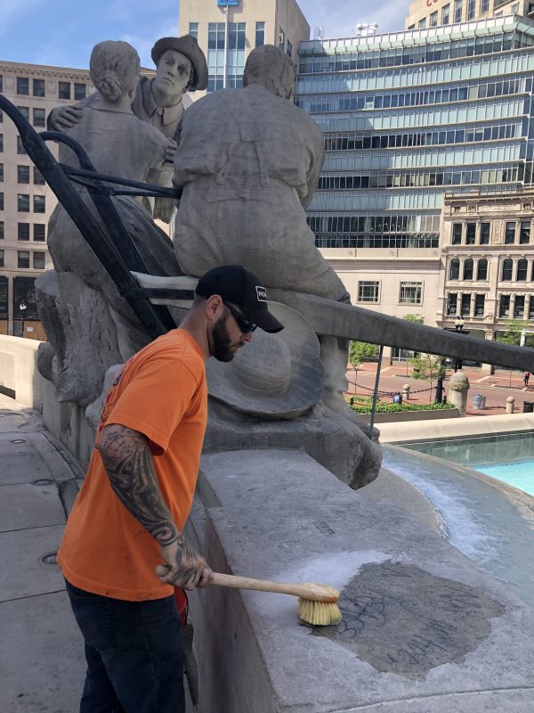 Chris Agal, a worker with Indianapolis-based masonry contractor Broady-Campbell, scrubs graffiti Monday from the Soldiers and Sailors Monument. (IBJ photo/John Russell)