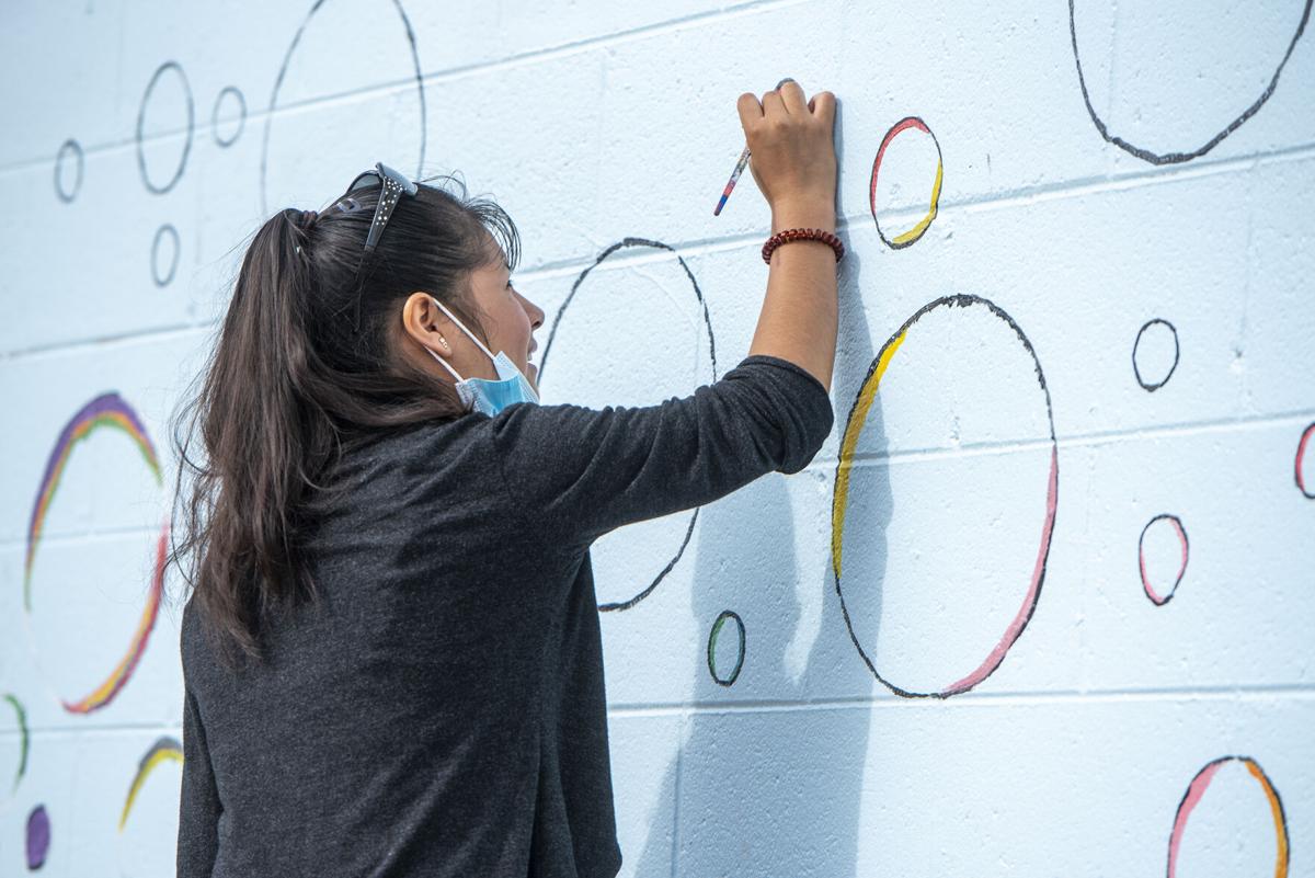 Apolonia Martin helps paint bubbles on a new mural on Sixth Street in Logansport. Staff photo by Tony Walters