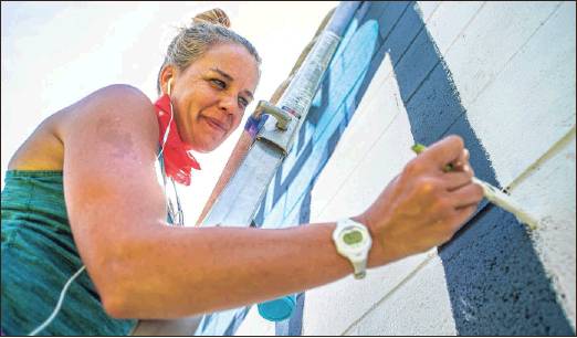 Chelsea Sanders works on a mural June 1 on the side of Cardinal Spirits. (Rich Janzaruk / Herald-Times)