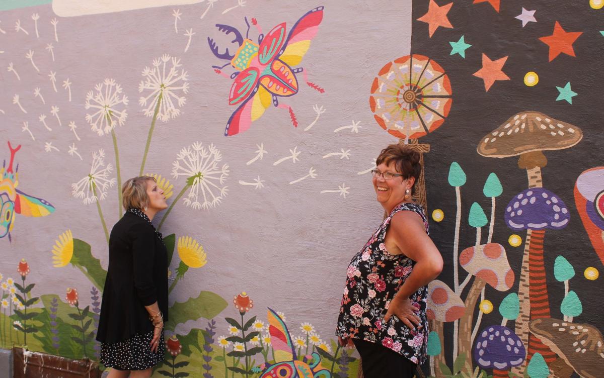 Kendallville Mayor Suzane Handshoe, left, and Kendallville Area Chamber of Commerce Executive Director Kristen Johnson pose for a photo in front of a mural in The Alley, which was painted by Johnson's daughter and former MYAC member Carmen Johnson. Staff photo by Steve Garbacz