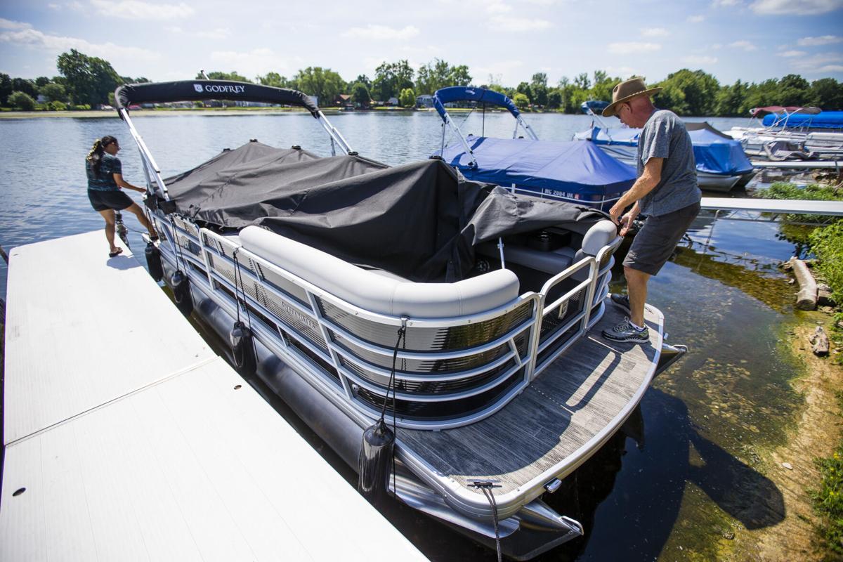 First-time boaters Scott and Merale Gayman uncover their new tritoon boat Friday at Wyland's Mishawaka Marine on the St. Joseph River. Staff photo by Michael Caterina