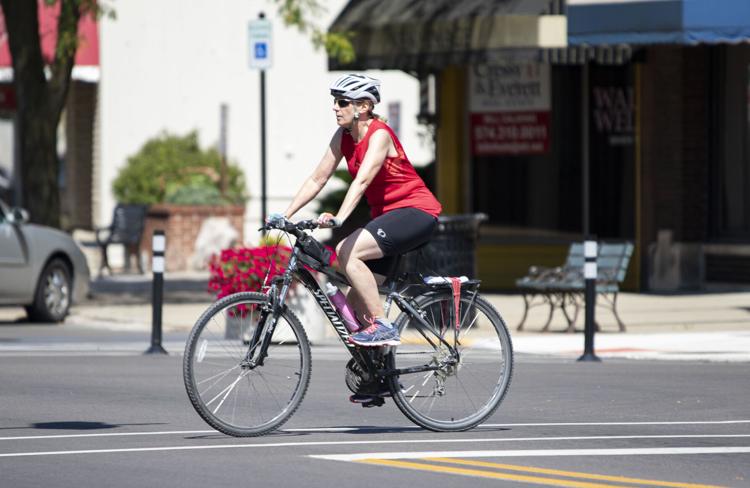Joyce Grinczel, of Goshen, rides her bike Friday afternoon through the intersection of North Main Street and West Clinton Street in Goshen. The city government is working on a climate action plan to reduce carbon emissions. Staff photo by Joseph Weiser 

   