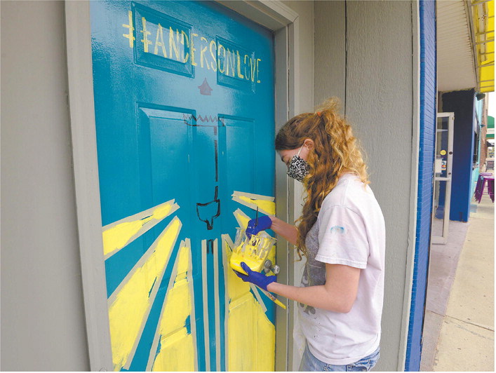 helby Nower paints a mural on a door on Meridian Street in downtown Anderson

on Sept. 11. Nower, a recent graduate of IUPUI’s Herron School of Art and Design, is one of four muralists commissioned by Anderson Indiana Main Street to design and paint murals downtown. Staff photo by Don Knight