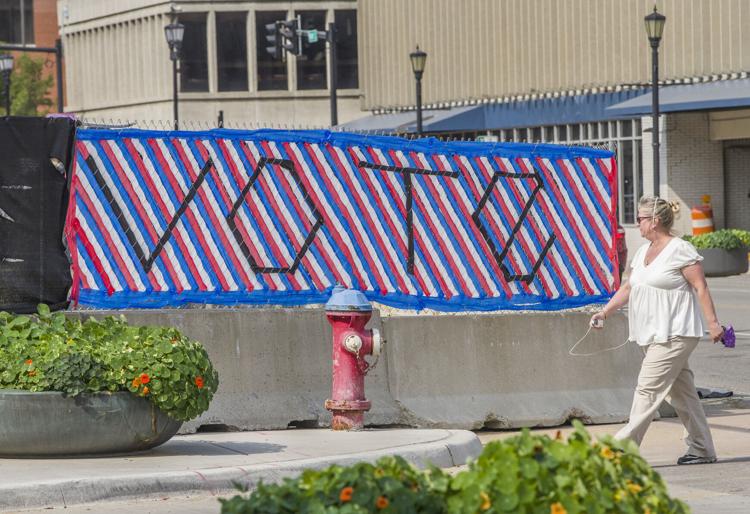 A woman walks by a large sign that reads “Vote” at the corner of Wayne and Michigan streets on Tuesday in downtown South Bend. Voter advocacy groups are making a push to get more young voters registered. South Bend Tribune Photo/ROBERT FRANKLIN