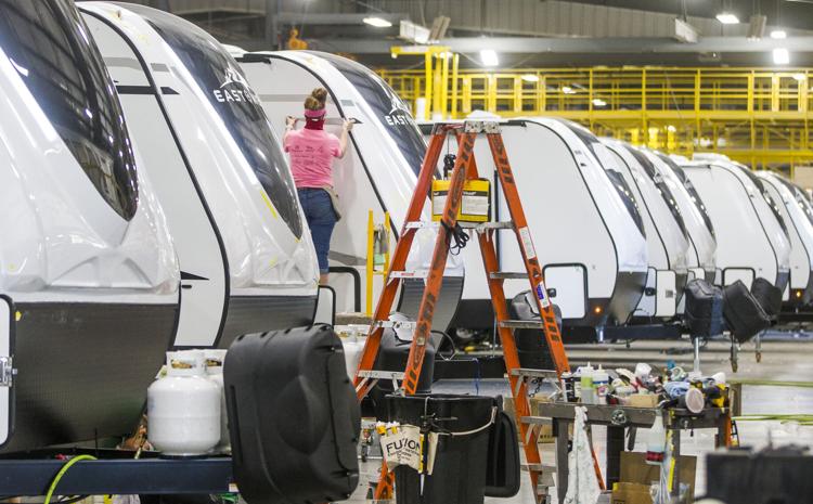 A worker installs graphics on an RV inside an East to West RV factory in Elkhart. RV shipments have rebounded sharply because of the coronavirus pandemic and are expected to set a new record in 2021. Staff photo by Robert Franklin