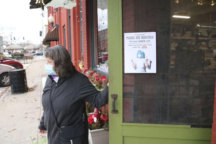 Susie Neff, Goshen, walks out of The Soapy Gnome, 111 E. Washington St., where a sign states facemasks are required to be worn in the store. Staff photo by Aimee Ambrose