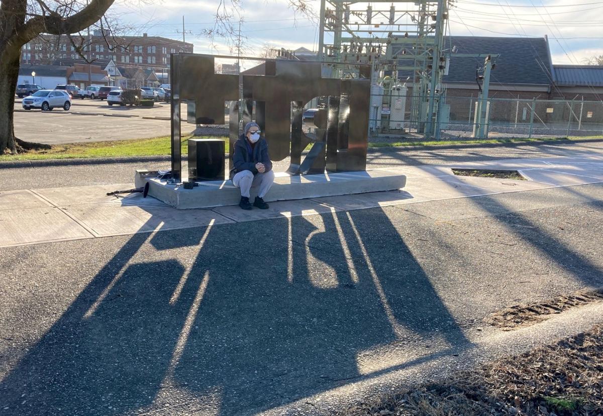 Local artist Amy DeLap sits on a new art installation erected on Riverwalk in Vincennes on Wednesday afternoon. Titled 'Truth Inside.' the word 'truth,' is spelled out in the shadow it creates. The piece was down by Oregon artist MacRae Wylde. Contributed photo