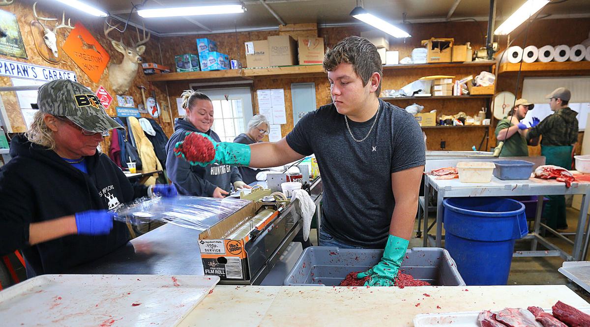 Frank Simpson processes deer for Farmers and Hunters Feeding The Hungry out of his deer-processing business in Young America on Nov. 24, 2020. Kristie Simpson gets plastic wrap ready as Braxton Larke balls ground venison to be wrapped. Staff photo by Tim Bath