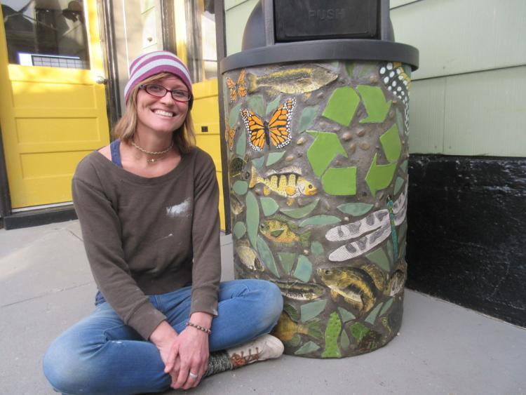 Janelle Slone of Pleasant Lake sits with her completed Arts in the Parks creation at the Relic Emporium in Angola. The recycle bin project included about 50 people of all ages and will be set at the boat launch area at Chain O’ Lakes State Park. Staff photo by Amy Obelin