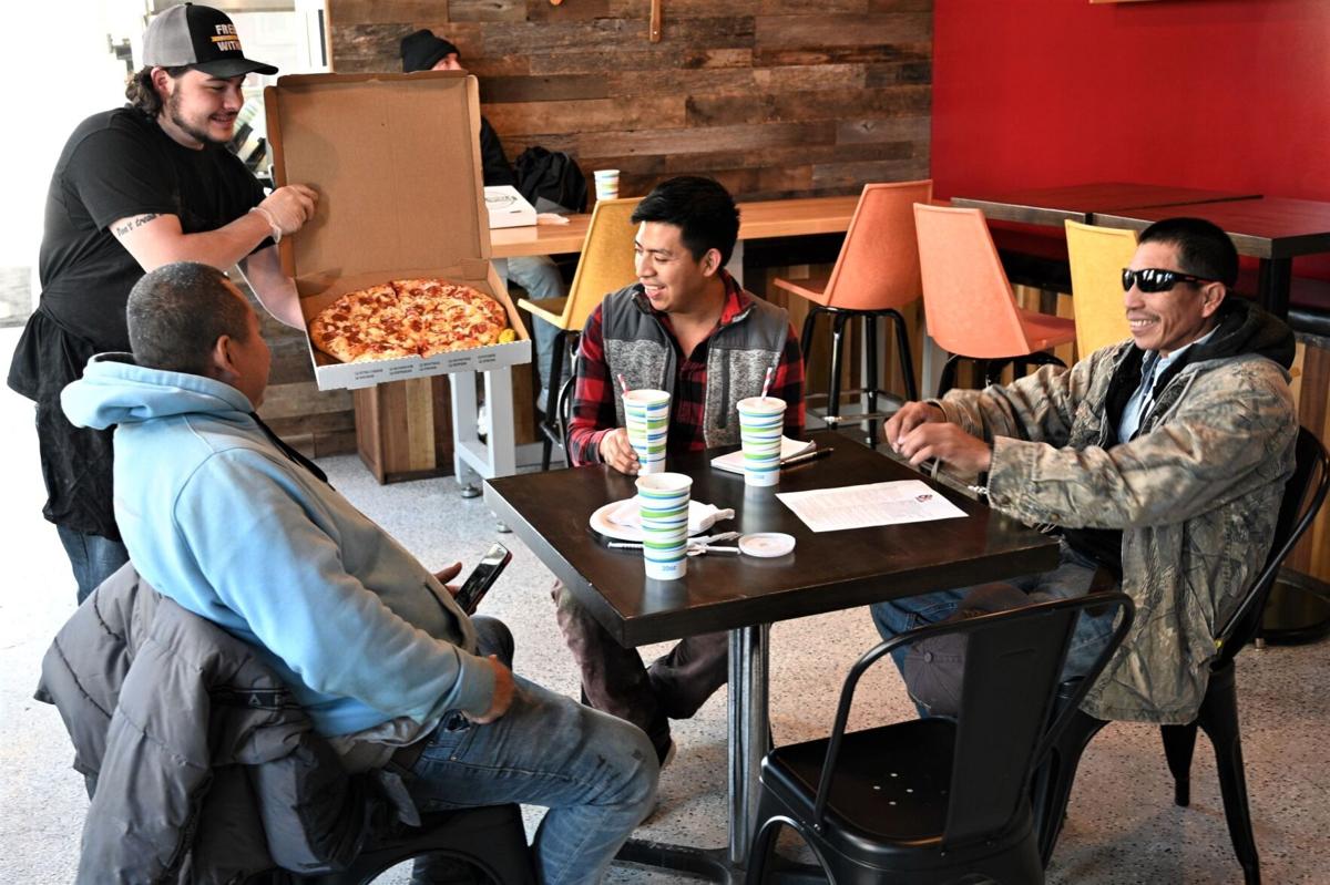 William Little of 8th Street Pizza serves a pie to customers (from left) Ruben Martines, Eduardo Az and Samuel Garcia. The trio was having lunch at the New Albany restaurant Tuesday afternoon. Staff photo by Bill Hanson