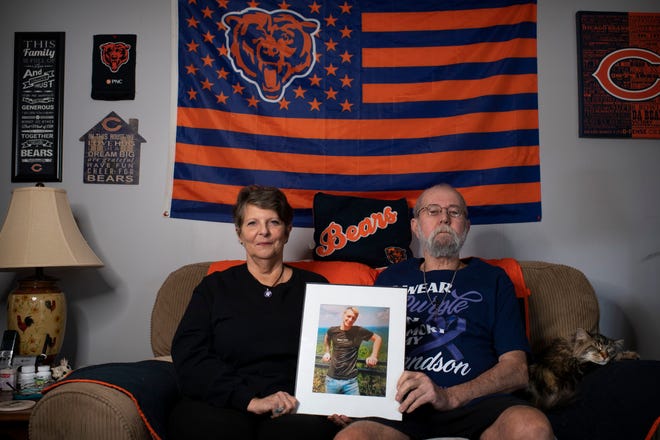 Grandparents Jean and James Carter hold a picture of James 'J.' Carter, their grandson, in their Boonville home Friday afternoon, Jan. 14, 2022. Granddad and grandson shared a love of things Chicago Bears and decked out the elder's home each football season with collectables they'd amassed. J. died from fentanyl overdose on June 5, 2021. Staff photo by Denny Simmons