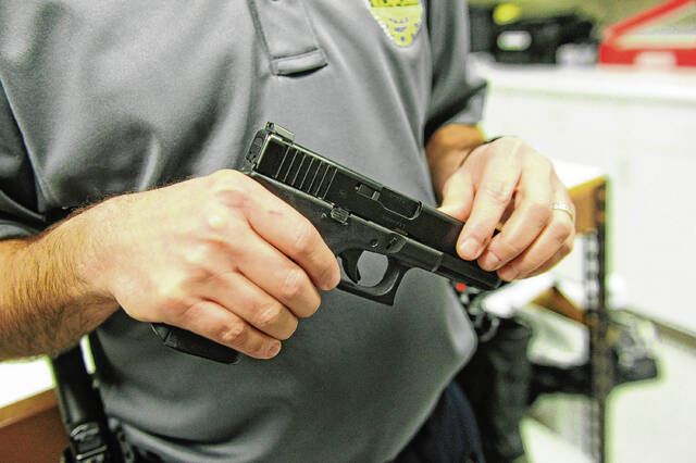 Chuck McMichael, deputy chief of the Greenfield Police Department, looks over a handgun confiscated during an investigation. As a practical matter, McMichael said, the proposed law could hinder police investigations. Staff photo by Tom Russo