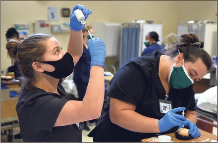 Applying what they learned: Ivy Tech Community College nursing student Jamie LaMaster fills a syringe as fellow student Megan Query practices administering an injection during their nursing lab on Wednesday in the Ivy Tech TechLAB in the industrial park. Tribune-Star/Joseph C. Garza