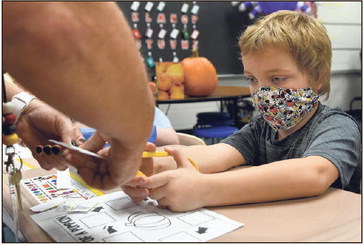 A helping hand: Lost Creek Elementary School student Bryson Cottom cuts out a paper pumpkin with some help from special education teacher Jodie Buckallew during class on Oct. 5, 2021, at the school. Tribune-Star file/Joseph C. Garza