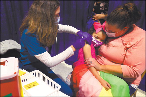 Seven year-old Tiana Shelton gets her first COVID-19 vaccination in November at the Howard County Health Department clinic at the Kokomo Event & Conference Center. Her mother, Whittney Carie, holds her as nurse Suzannah Leight gives her the shot. Staff photo by Tim Bath