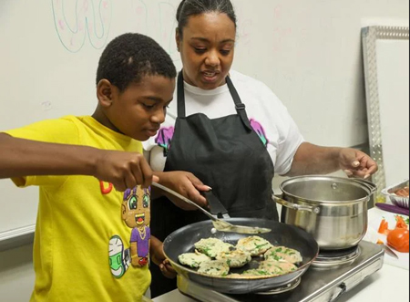 Under supervision from Nakia Bonds, 11-year-old Deriyon Davis cooks turkey burgers as part of the FIT-Together program at the Michigan City Elston YMCA. Staff photo by John J. Watkins
