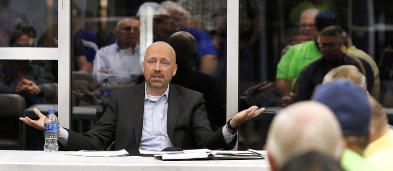 Joe Hoage, Commissioner of the Indiana Bureau of Motor Vehicles talks to residents as their reflections surround him during a public hearing by the BMV on Wednesday about a proposal to close the Hobart license branch. The meeting took place at the city's Community Center in Festival Park on Oct. 5, 2022. (John Smierciak/Post Tribune)