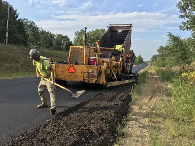 Workers with E&B Paving apply asphalt grindings to the shoulder of County Road 50W in Fremont in this August 2020 staff file photo by Mike Marturello