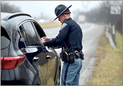 Indiana State Police Trooper Tyler Turchi looks over a motorist’s driver’s license along Indiana 63 near Clinton on Friday during a traffic stop. Tribune-Star/Joseph C. Garza