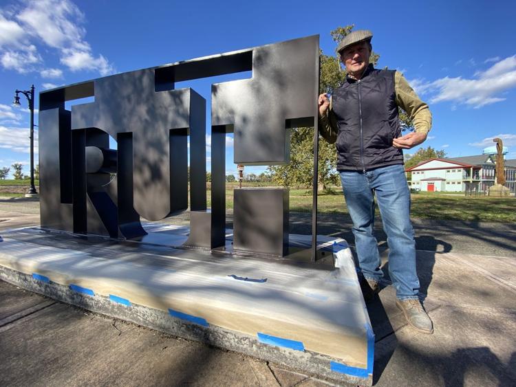 Artist MacRae Wylde poses with his sculpture, “Truth Inside,” after it was installed in the fall of 2021. The 5’ x 11’ steel sculpture on the city’s Riverwalk, among the first to be erected as part of the First City Public Sculpture Exhibition, is currently for sale. A buyer will need to come forward before this summer or it will be returned to the artist. Sun-Commercial file photo
