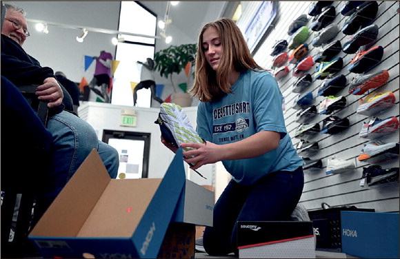 Pacesetter Sports salesperson Emma Gard prepares another shoe for customer Larry Toppin of Seelyville on Thursday at the sporting goods store on south Third Street. Brent Compton, who owns Pacesetter Sports with his wife, Jennifer, said he thinks 2023 “is looking to be very stable.” Tribune-Star/Joseph C. Garza