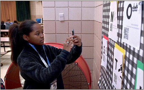 Sarah Scott Middle School sixth-grader Sejus Suggs demonstrates how she is able to use a smart phone to scan a QR code on a display for Black History Month in the middle school’s lunchroom on Tuesday.  Tribune-Star/Joseph C. Garza