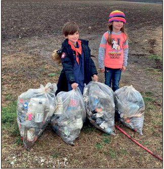 Six-year-old twins Anika and Isaac Backfish are learning early in life to pick up after themselves, and others, as they collected trash along a Vigo County roadway in March. Their parents, Aaron and Rachel Backfish, are also faithful Trash Baggers. Mike Lunsford photo