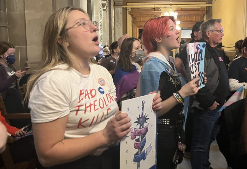  Annie DerOlf, left, and Killian Provence, a 16-year-old transgender boy, chant outside of the Senate Chamber against a bill that would bar gender-affirming medical care. (Whitney Downard/Indiana Capital Chronicle)