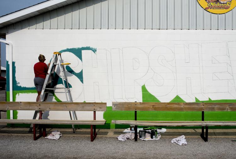 Artist Amy Psinas starts to paint the background of a new mural she was hired to create on the grounds of the Shipshewana Trading Place flea market. Public art, as it known, is going in rural communities thanks in part to a push by the state. Staff photo by Patrick Redmond