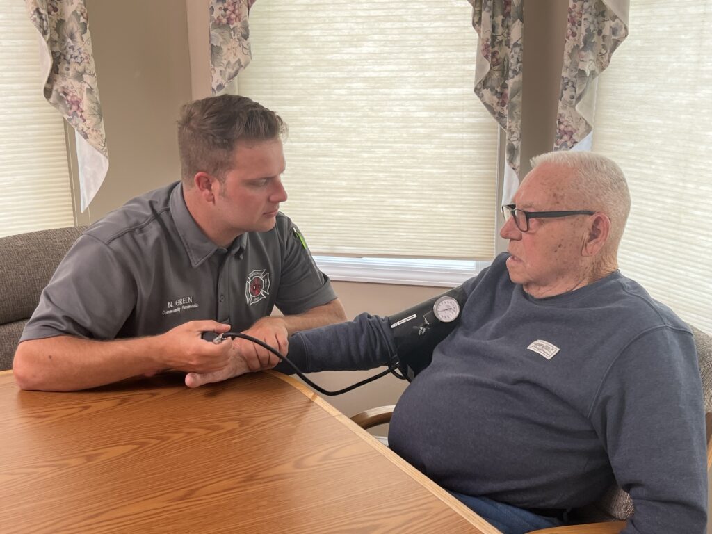 Nick Green (left), Monticello’s first mobile integrated health director, checks Skip Barnes' blood pressure. Whitney Downard photoa