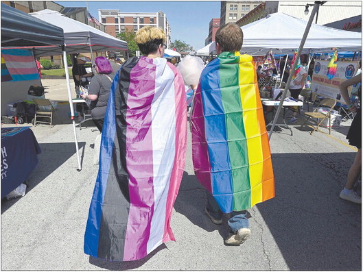 Cloaked in pride flags, Hunter Petty of Montezuma and Cameron Swinford of Diamond walk through the stands set up for Pride Fest on June 4, 2022, on Wabash Avenue. Staff file photo by Joseph C. Garza | CNHI News Indiana